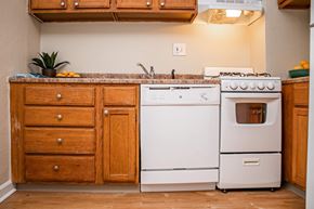 St. Louis apartment for rent - A white dishwasher and oven sit next to a sink in a kitchen.