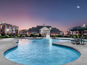 Oklahoma City apartment for rent - a swimming pool with a fountain at night with a building in the background