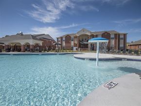 Yukon apartment for rent - a large pool with an umbrella in front of some apartments