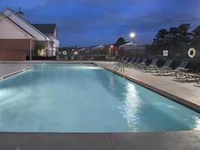 Bryant apartment for rent - the swimming pool at night with chairs around it