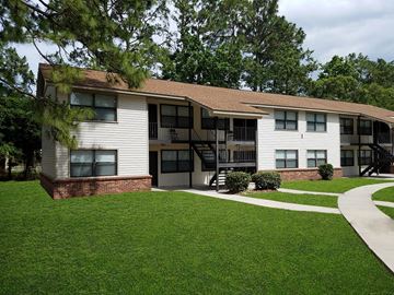 Savannah apartment for rent - A white building with a brown roof and a green lawn in front.