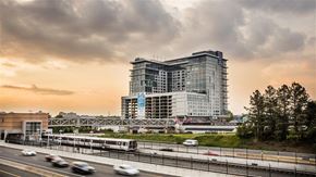 Reston apartment for rent - a high rise building next to a freeway and a train
