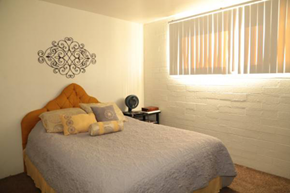Scottsdale apartment for rent - A bedroom with a bed, a wall clock, and a decorative piece on the wall.