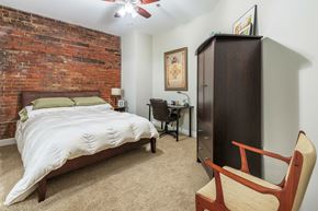 Greenville apartment for rent - a bedroom with a bed and a brick wall    and a dresser