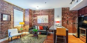 Greenville apartment for rent - a living room with a kitchen and a exposed brick wall
