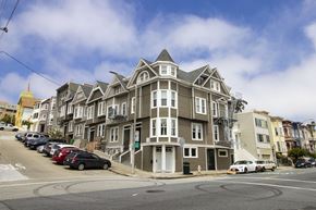 San Francisco apartment for rent - A large, multi-story building with a grey and white exterior sits on a street corner.