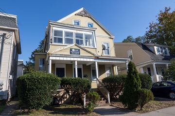 New Haven apartment for rent - A two-story house with a front porch and a car parked in the driveway.