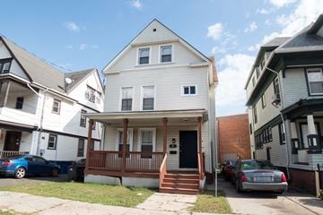 New Haven apartment for rent - A white house with a porch and a car parked in front.
