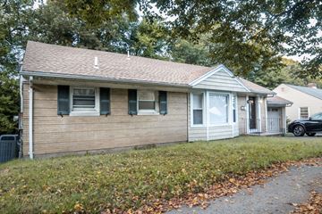 New Haven apartment for rent - A small house with a brown roof and a white door is surrounded by trees and has a car parked in the driveway.