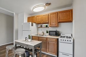 Denver apartment for rent - A kitchen with a white fridge, white stove, and wooden cabinets.