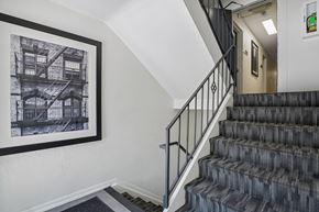 Denver apartment for rent - A staircase with a black railing and a picture of a building on the wall.
