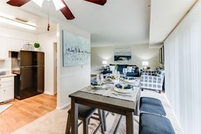 Huntsville apartment for rent - A dining area with a table set for two and a refrigerator in the corner.