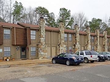 Tuscaloosa apartment for rent - A car is parked in front of a building with stone pillars.
