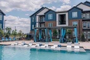 Madison apartment for rent - A swimming pool in front of a multi-story building with blue umbrellas.