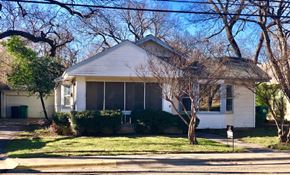 Denton house for rent - A house with a white siding and a grey roof is surrounded by trees.