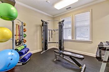 A home gym with a variety of equipment including a squat rack, exercise balls, and resistance bands.