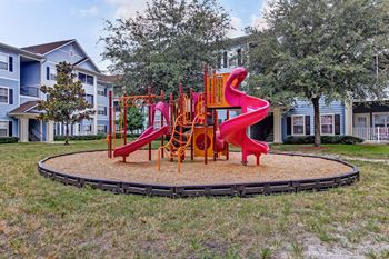 A playground with a red slide and orange climbing structure.