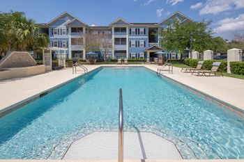 A large swimming pool in front of a multi-story apartment building.