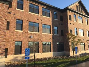 St. Cloud apartment for rent - A red brick building with a blue and white handicap sign in front.