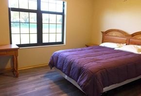 St. Cloud apartment for rent - A bed with a purple comforter sits in a room with a window.