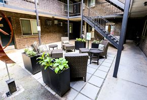 Denver apartment for rent - an outside patio with tables and chairs and a brick building