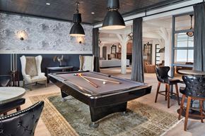 Amityville apartment for rent - A pool table is in the middle of a room with a black leather chair and a rug.