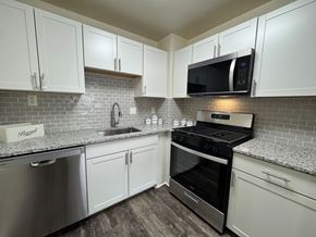Alexandria apartment for rent - A kitchen with white cabinets and a black stove top oven.