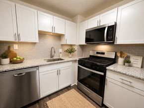 Alexandria apartment for rent - A kitchen with white cabinets and a black stove top oven.