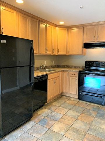 South Portland apartment for rent - A black refrigerator is in a kitchen with wooden cabinets.