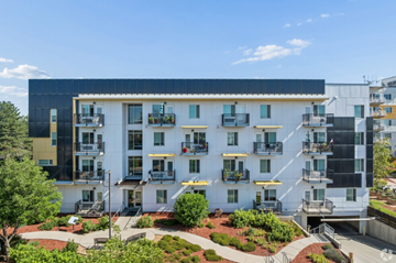 Lakewood apartment for rent - A modern apartment complex with white and black buildings and a red brick courtyard.