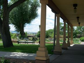 Lakewood apartment for rent - A porch with columns and a bench under a tree.