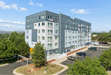 Lakewood apartment for rent - A large grey building with a parking lot in front.
