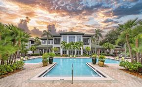 Tampa apartment for rent - a large swimming pool in front of a building with palm trees