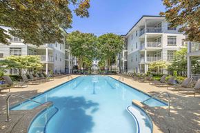 Atlanta apartment for rent - A large swimming pool surrounded by lounge chairs and trees.
