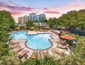 Mclean apartment for rent - A large outdoor pool surrounded by wooden loungers and umbrellas.