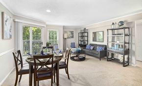 Mclean apartment for rent - A dining room with a table set for four and a couch with a blue cushion.