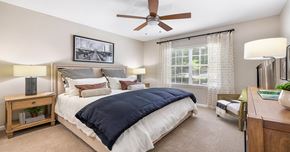 Charlotte apartment for rent - A bedroom with a bed, nightstand, and a ceiling fan.