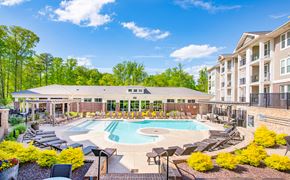 Raleigh apartment for rent - an outdoor pool with lounge chairs around it and an apartment building