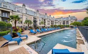Dallas apartment for rent - a swimming pool with blue chairs and a sunset in the background