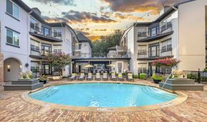 Dallas apartment for rent - A swimming pool surrounded by a brick patio and lounge chairs.