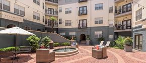 Dallas apartment for rent - a courtyard with a fountain and patio furniture in front of an apartment building