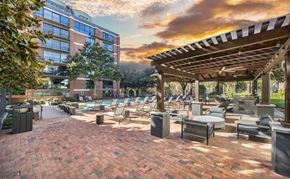 Dallas apartment for rent - a patio with tables and chairs and a building with a sunset in the background