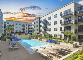 Dallas apartment for rent - a swimming pool in front of an apartment building at sunset