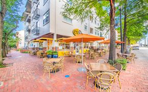 Houston apartment for rent - a patio with tables and umbrellas in front of an apartment building