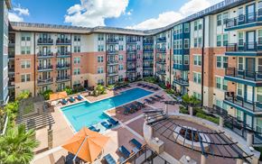 Houston apartment for rent - an outdoor pool with umbrellas and an apartment building