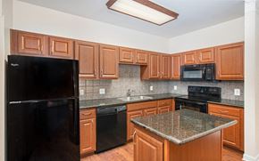 Austin apartment for rent - a kitchen with wood cabinets and black appliances and granite counter tops