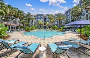 Tampa apartment for rent - a swimming pool with lounge chairs and umbrellas in front of an apartment building