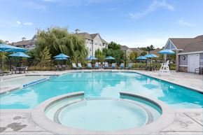 Burlington apartment for rent - a swimming pool with chairs and umbrellas in front of a house