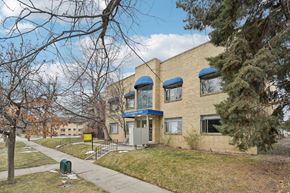 Denver apartment for rent - A building with a blue awning and a yellow sign on the front.