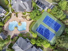 Duluth apartment for rent - an aerial view of a tennis court and pool in a backyard with trees
